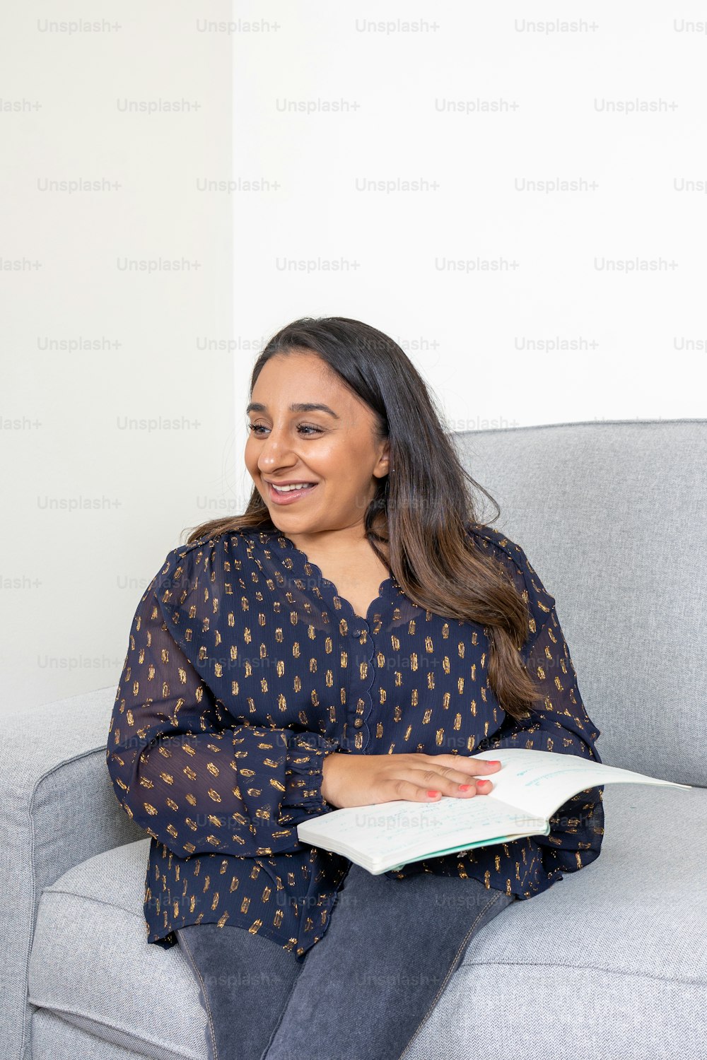 a woman sitting on a couch holding a book