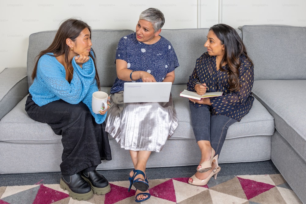 três mulheres sentadas em um sofá conversando entre si