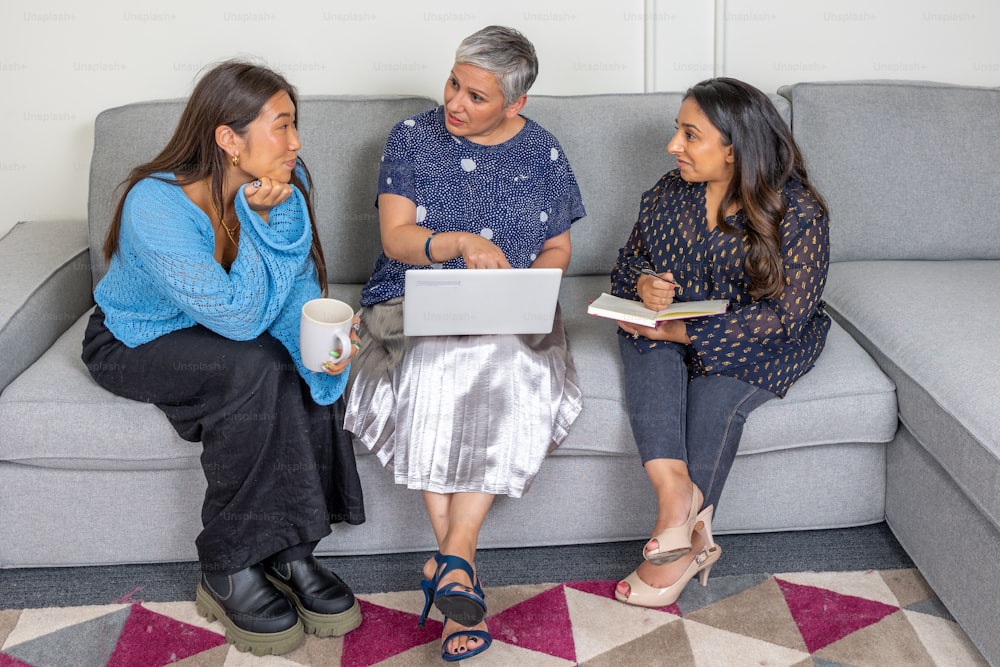 three women sitting on a couch talking to each other