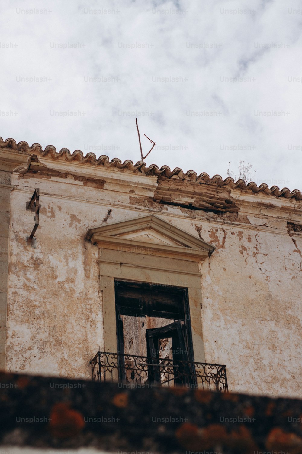 Un vecchio edificio con un balcone e una croce in cima
