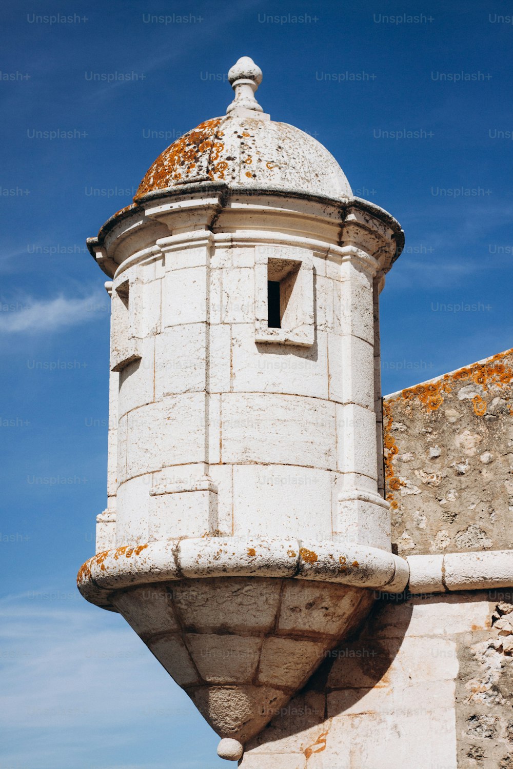 a white tower with a rusted roof against a blue sky