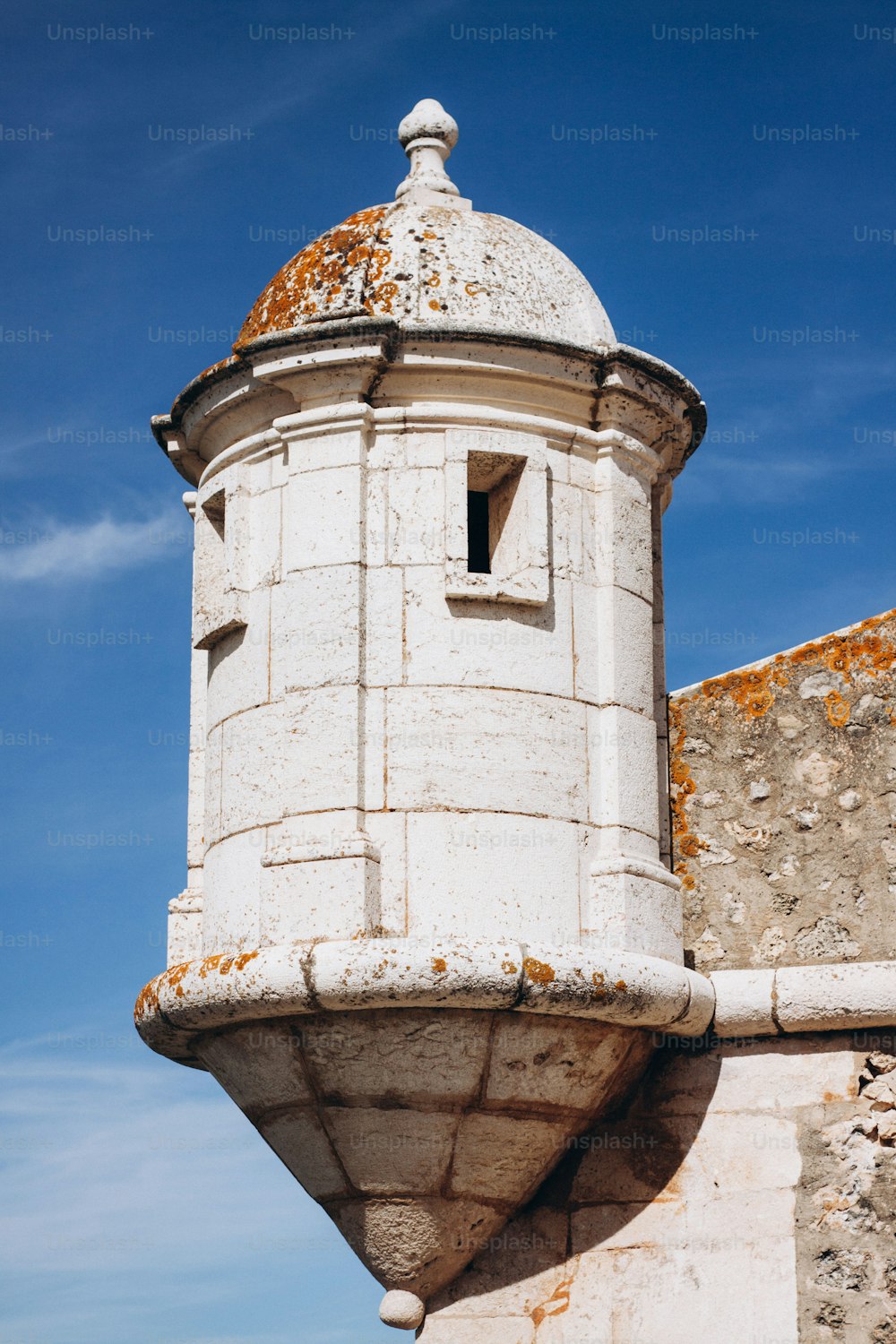 une tour blanche avec un toit rouillé contre un ciel bleu