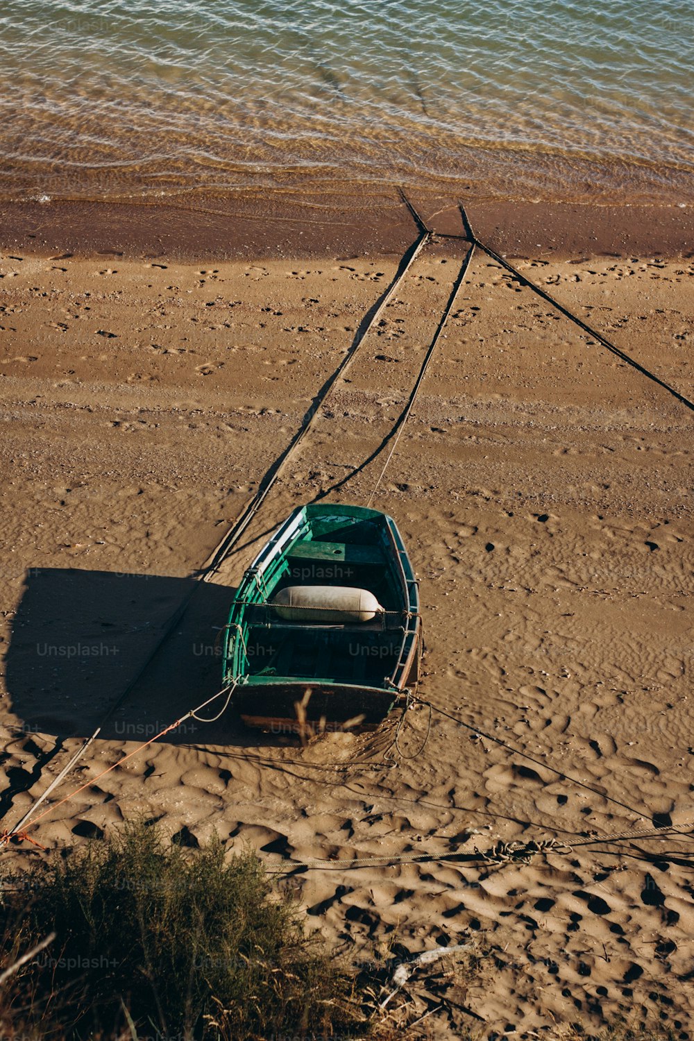 um barco verde sentado no topo de uma praia de areia