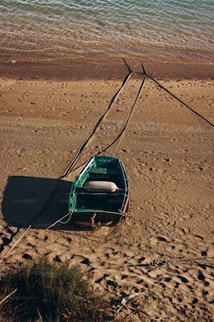 a green boat sitting on top of a sandy beach