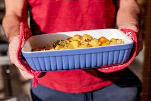 a person holding a blue dish of food