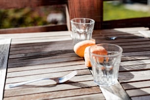 two oranges and a glass on a wooden table