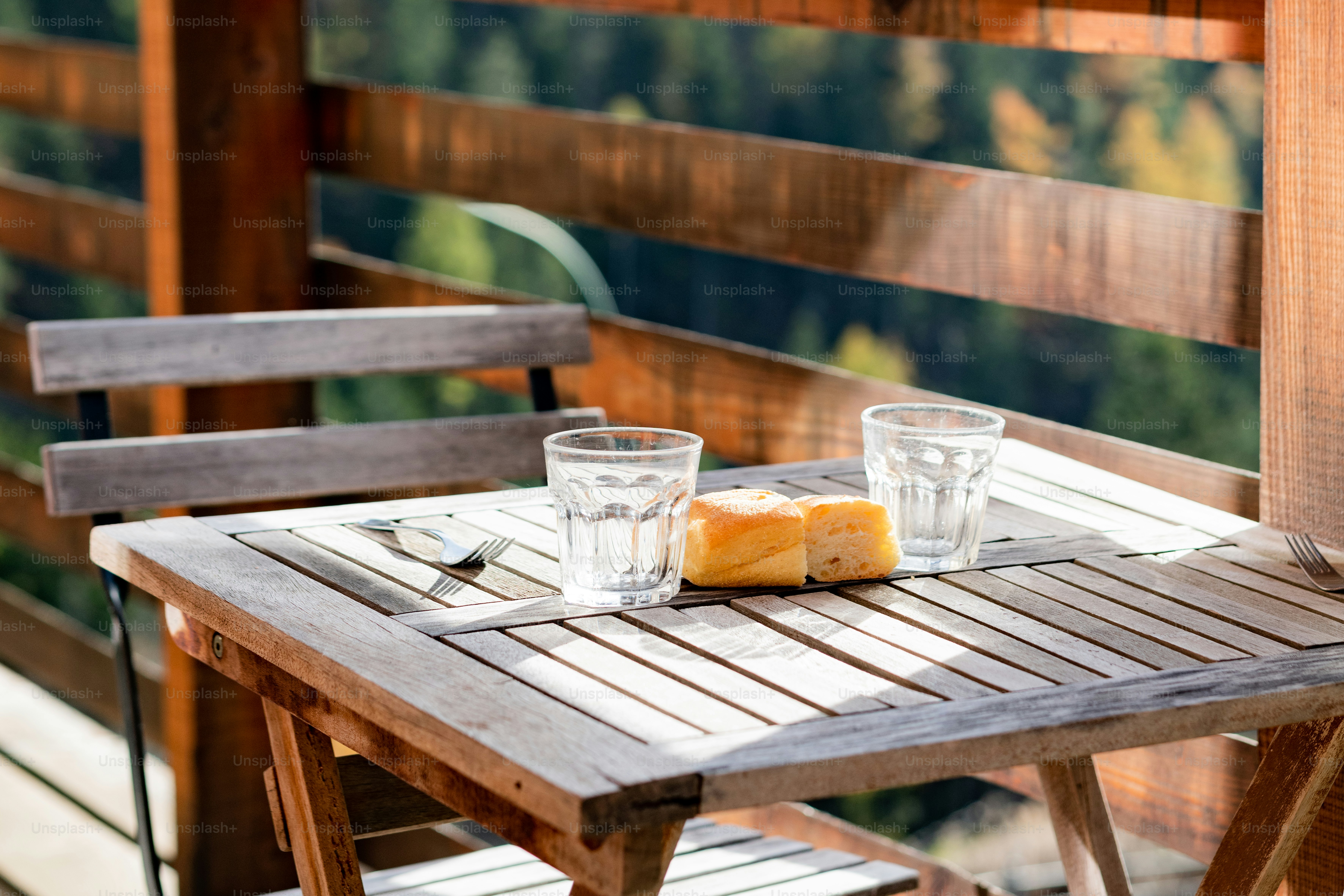 une table en bois avec deux verres et une miche de pain dessus