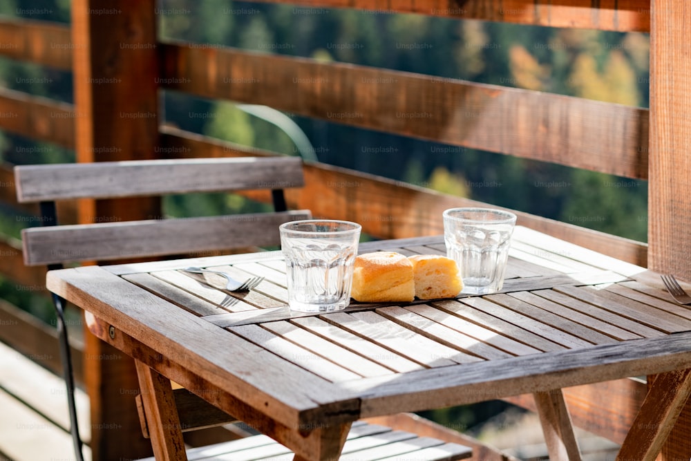 a wooden table with two glasses and a loaf of bread on it