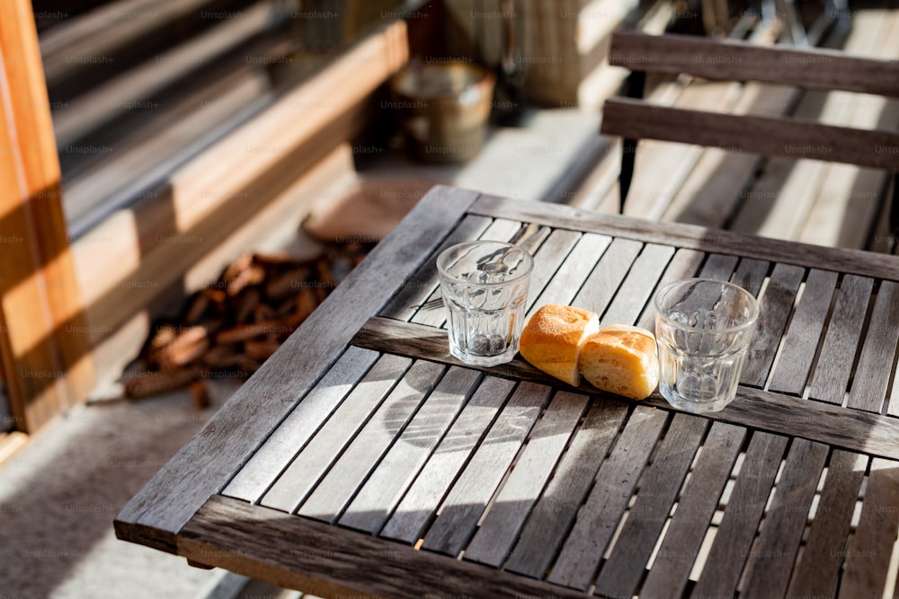 a wooden table topped with two glasses and a loaf of bread