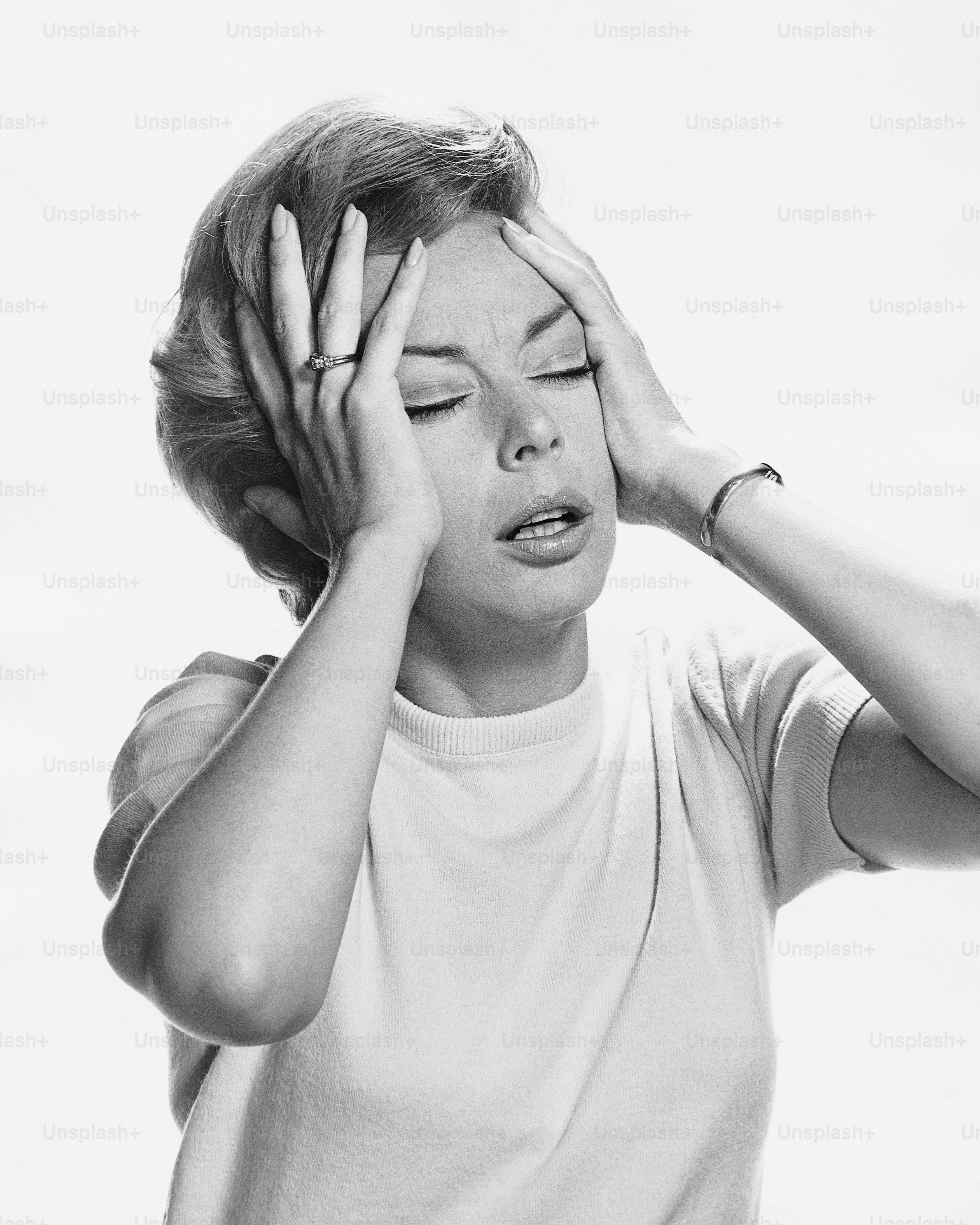 a black and white photo of a woman covering her eyes