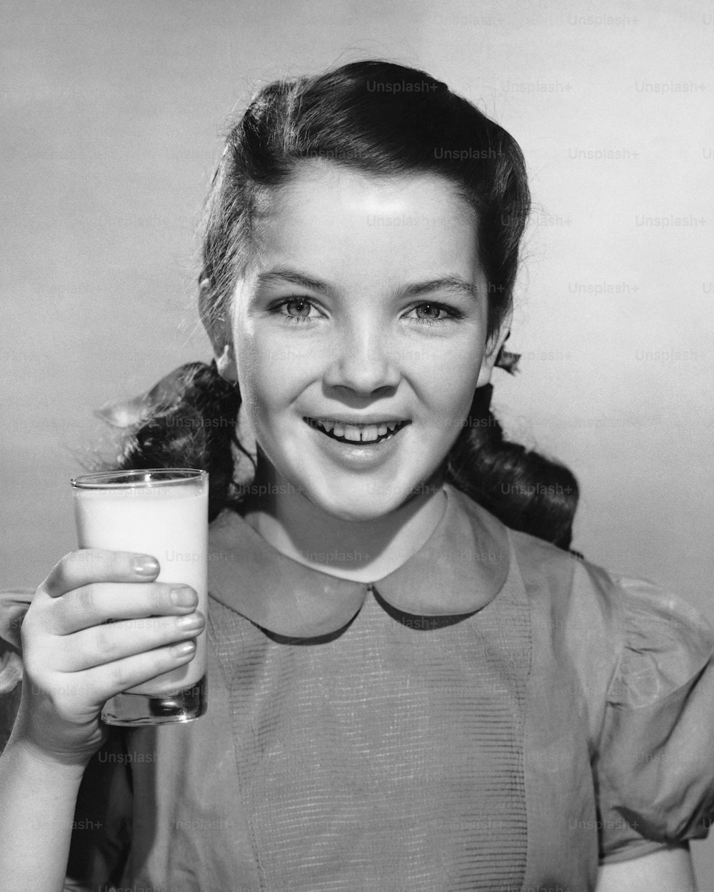 a young girl holding a glass of milk