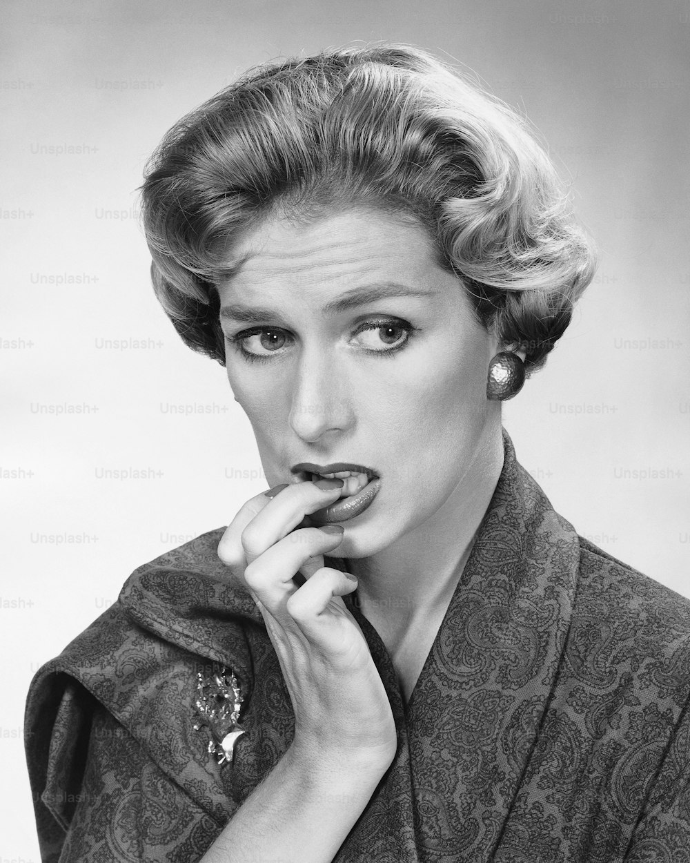a black and white photo of a woman biting into a cookie