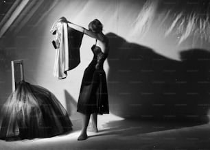 7 novembre 1951: una donna si prepara a indossare un vestito sopra una sottoveste di pizzo.  (Foto di Chaloner Woods/Getty Images)