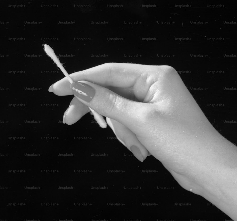 2. Mai 1961: Eine manikürte weibliche Hand mit einem Wattestäbchen, das zum Reinigen des Ohres bestimmt ist.  (Foto von Chaloner Woods / Getty Images)