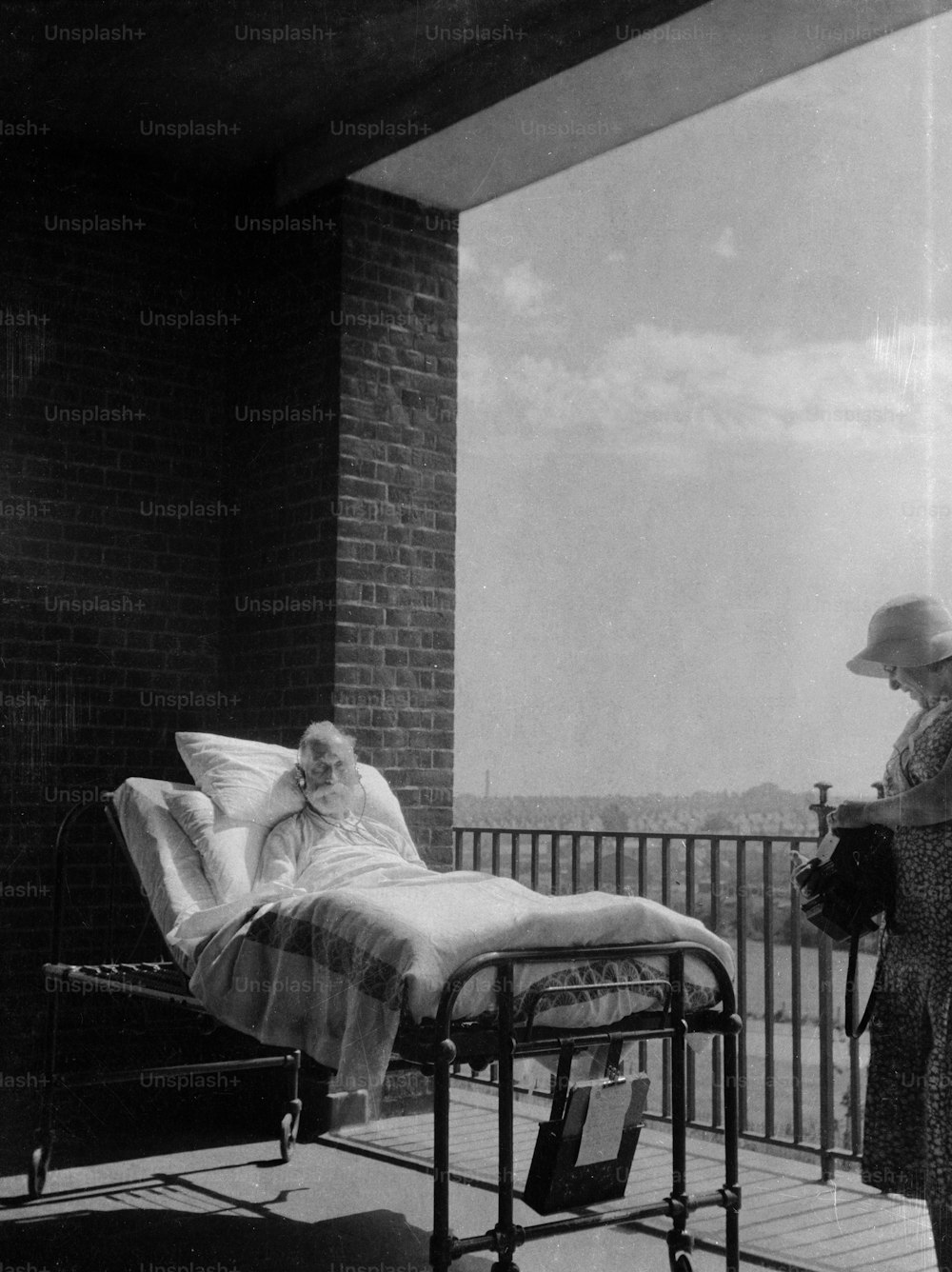 Hacia 1930: Un anciano convaleciente con su cama de hospital en un balcón, con el fin de acelerar su recuperación con aire fresco y saludable.  (Foto de Chaloner Woods/Getty Images)