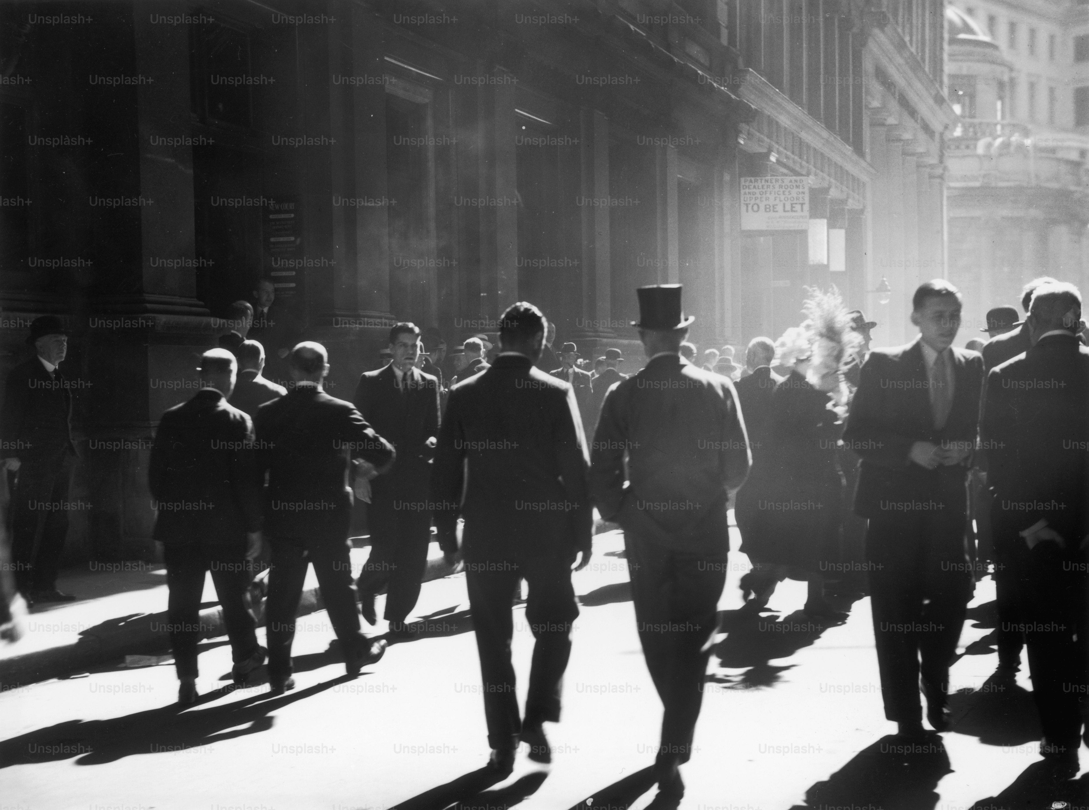 1938 circa: operai della città camminano fuori da New Court in Throgmorton Street, nel quartiere finanziario di Londra.  (Foto di Chaloner Woods/Getty Images)