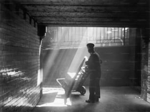 circa 1938:  A railway porter pushing his trolley through a sunbeam.  (Photo by Chaloner Woods/Getty Images)