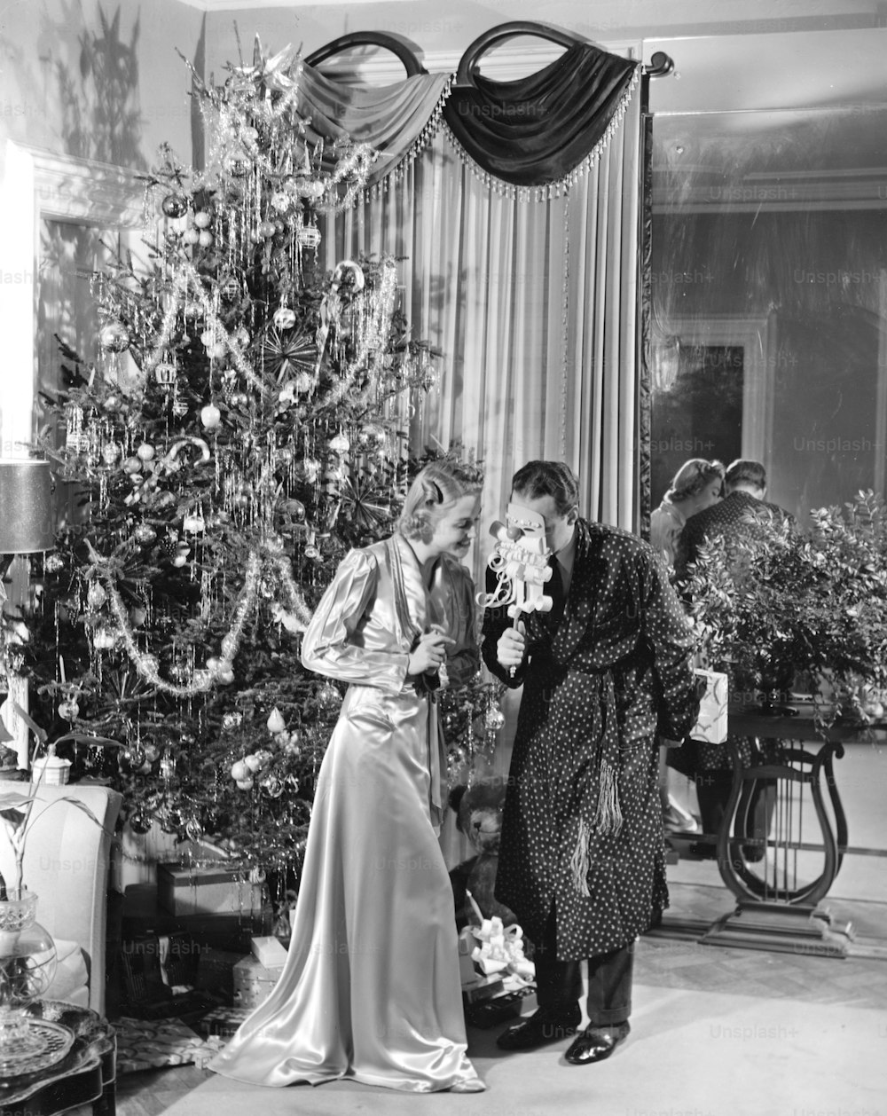 UNITED STATES - CIRCA 1950s:  Couple standing near Christmas tree with mask.