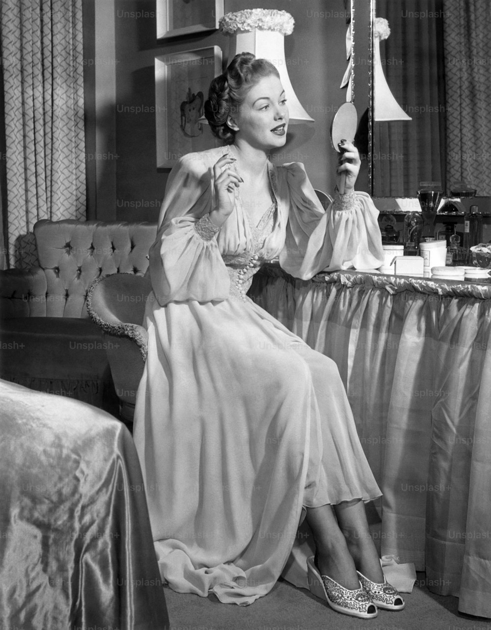 VEREINIGTE STAATEN - CIRCA 1950er Jahre: Eine Frau in ihrem Nachthemd schaut in den Spiegel.