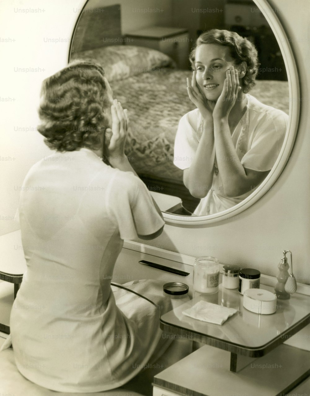UNITED STATES - CIRCA 1950s:  Woman looking in the mirror and touching her face.