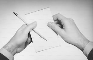 deux mains tenant un crayon et un morceau de papier