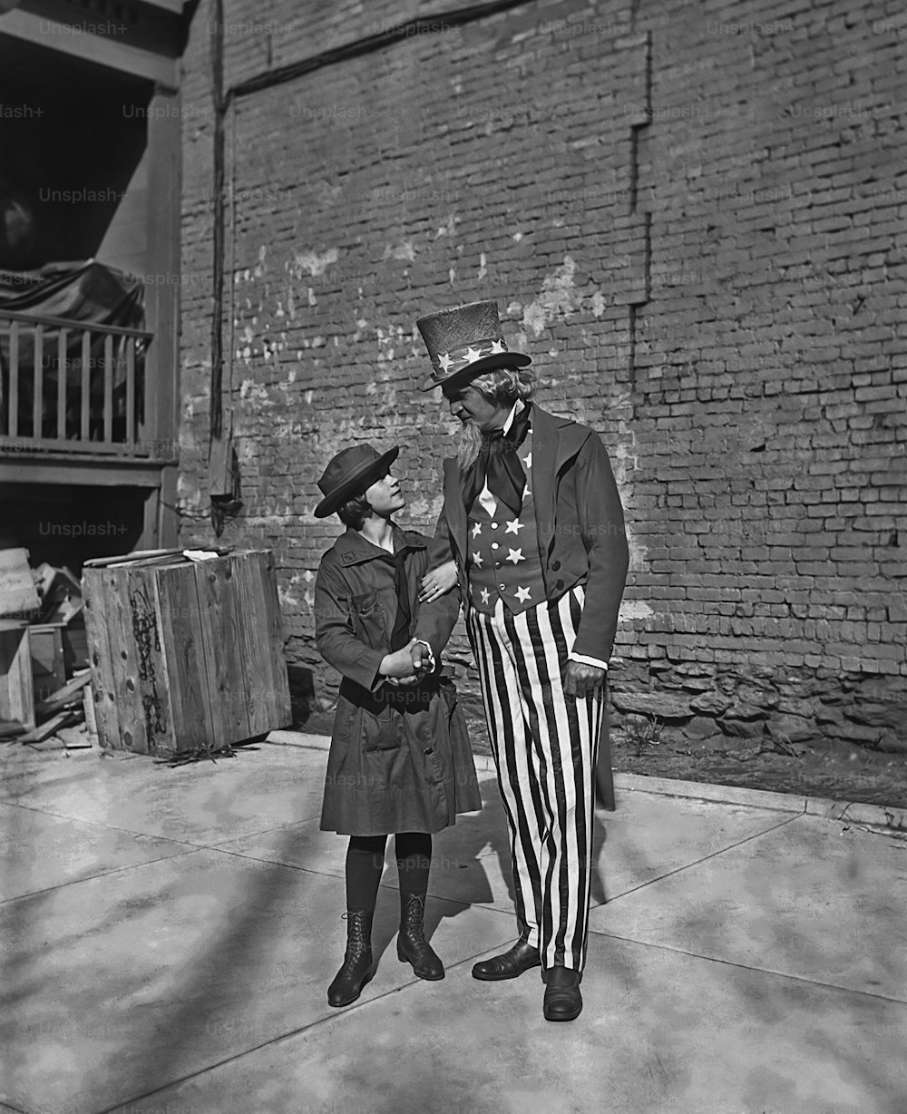Eine Pfadfinderin mit einem Mann, der um 1914 als Onkel Sam verkleidet ist. (Foto von FPG / Getty Images)