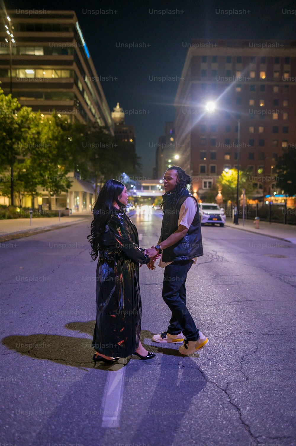 a man and woman standing on a city street at night