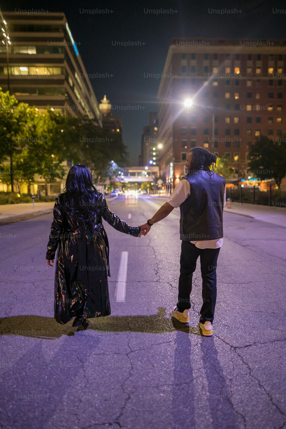 a man and a woman holding hands while walking down a street