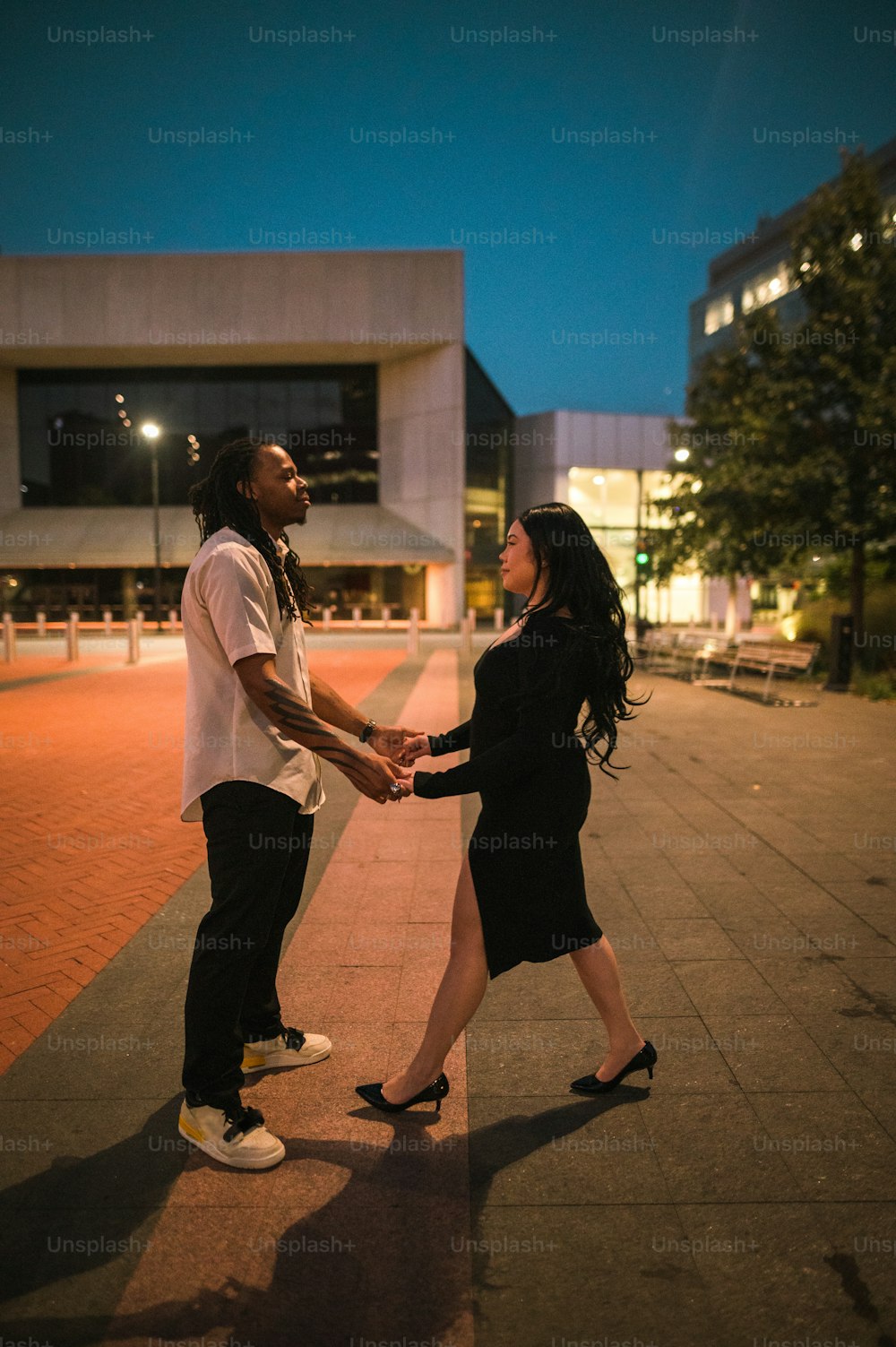 a man and a woman holding hands on a sidewalk