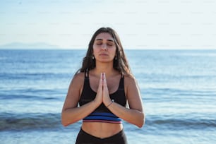 a woman standing in a yoga pose on the beach