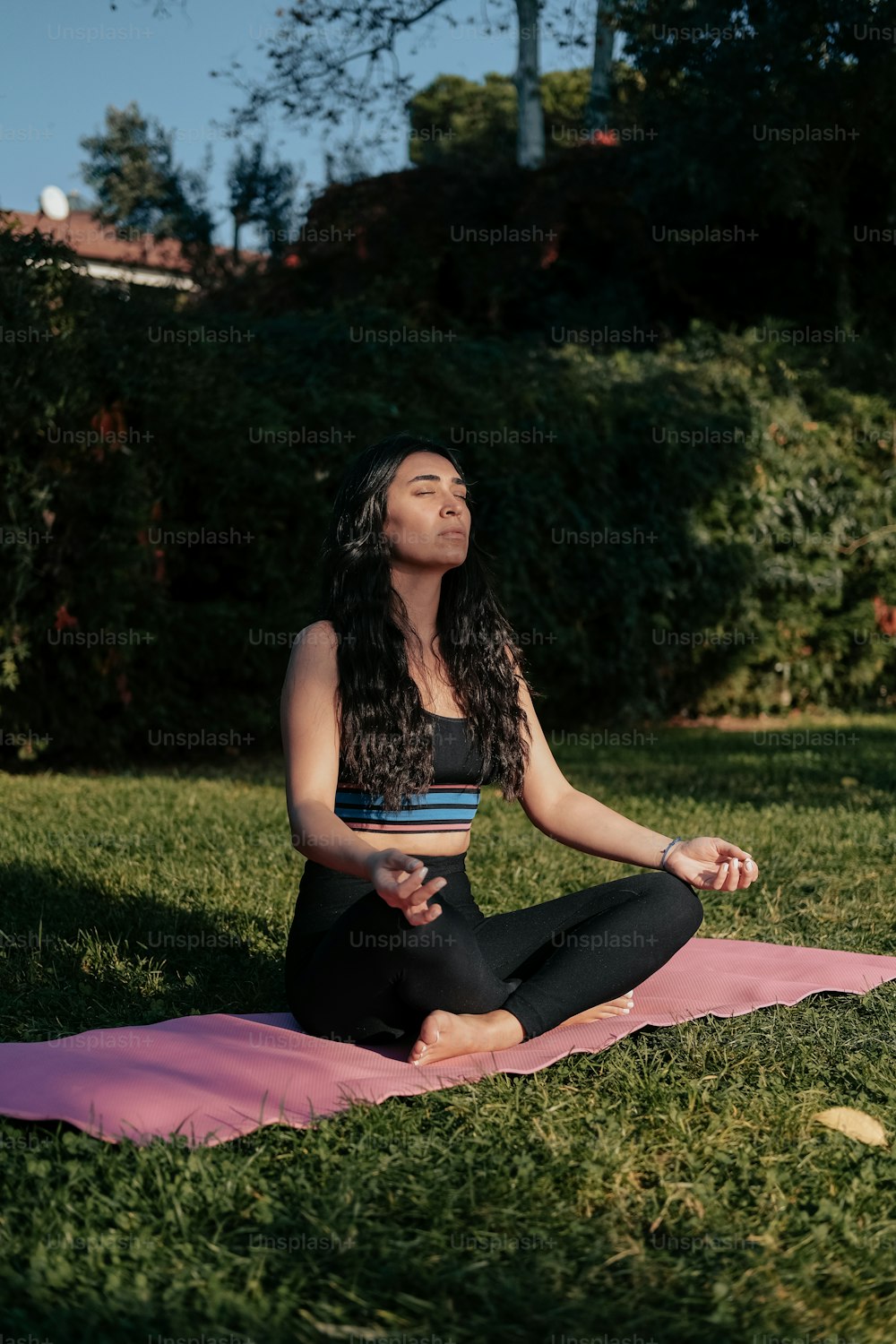 uma mulher sentada em um tapete de ioga em um parque