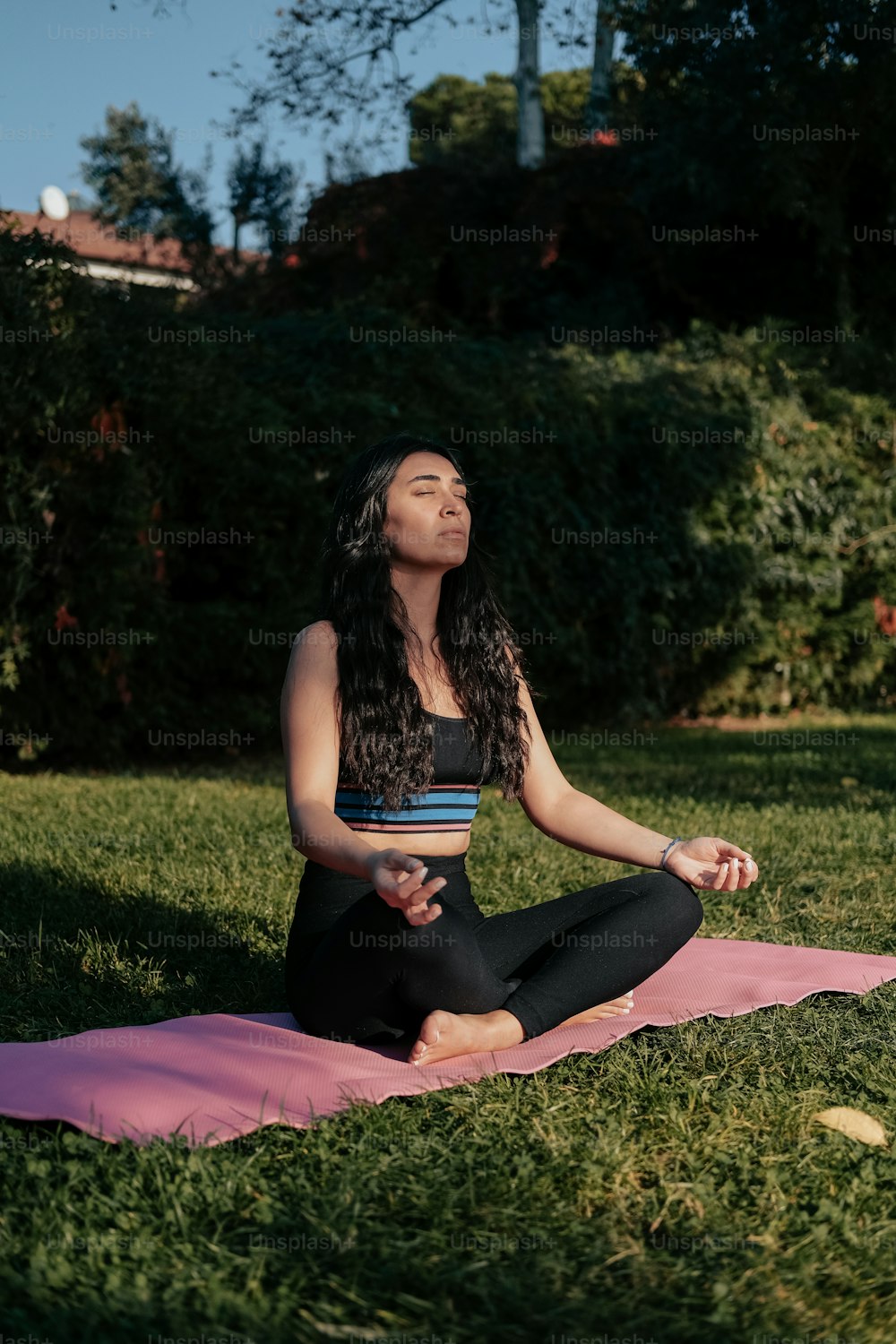 a woman sitting on a yoga mat in a park