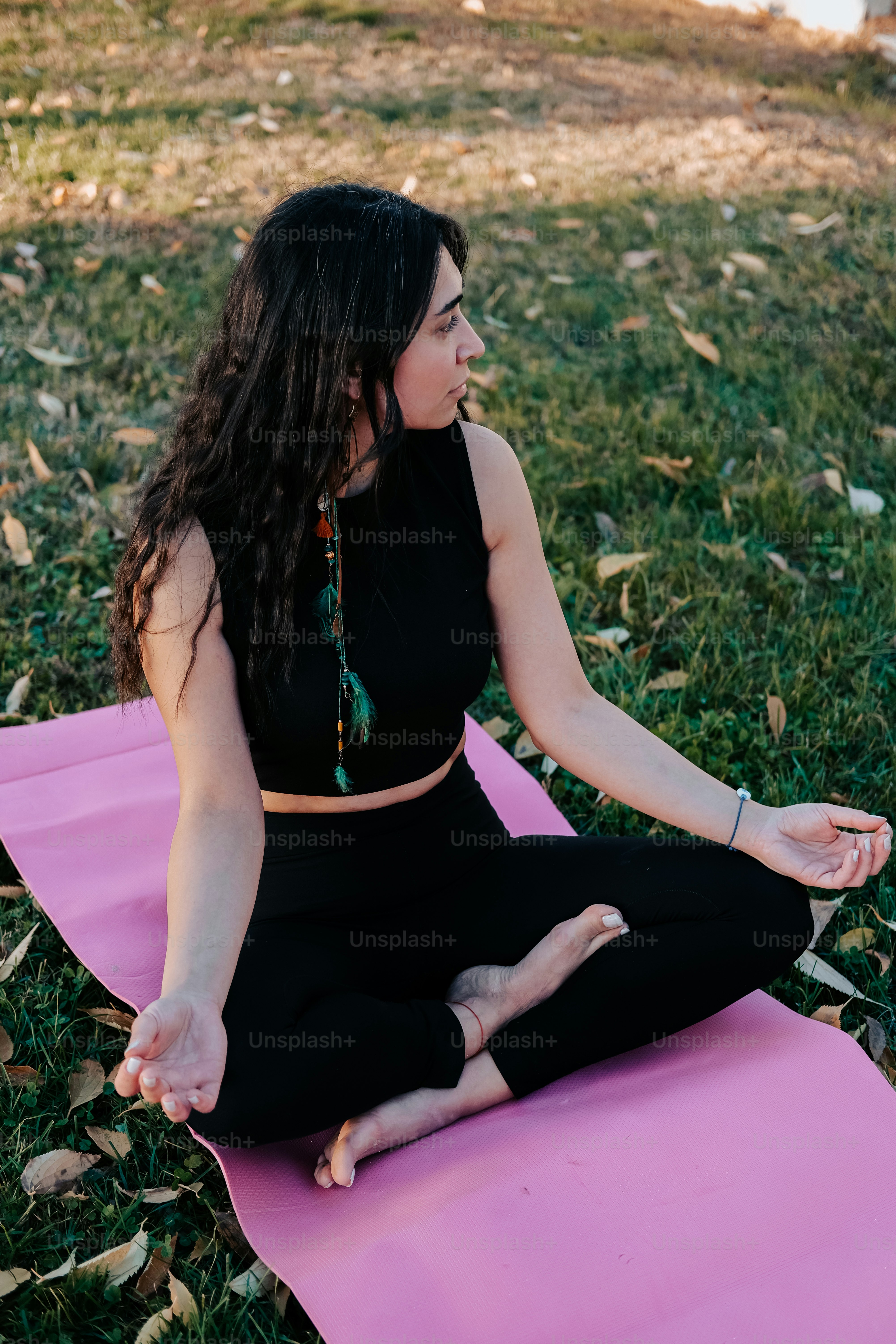 Eine Frau, die auf einer Yogamatte in einem Park sitzt