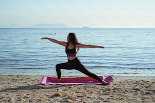 Una mujer está haciendo yoga en la playa