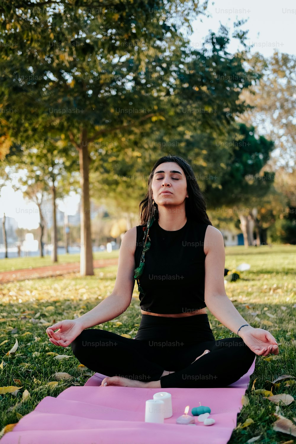 uma mulher sentada em uma posição de ioga em um parque