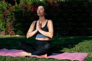 a woman sitting in a yoga position in the grass