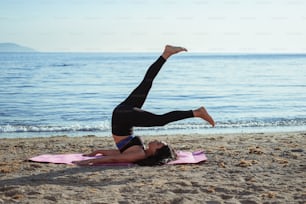 a woman doing a yoga pose on a beach