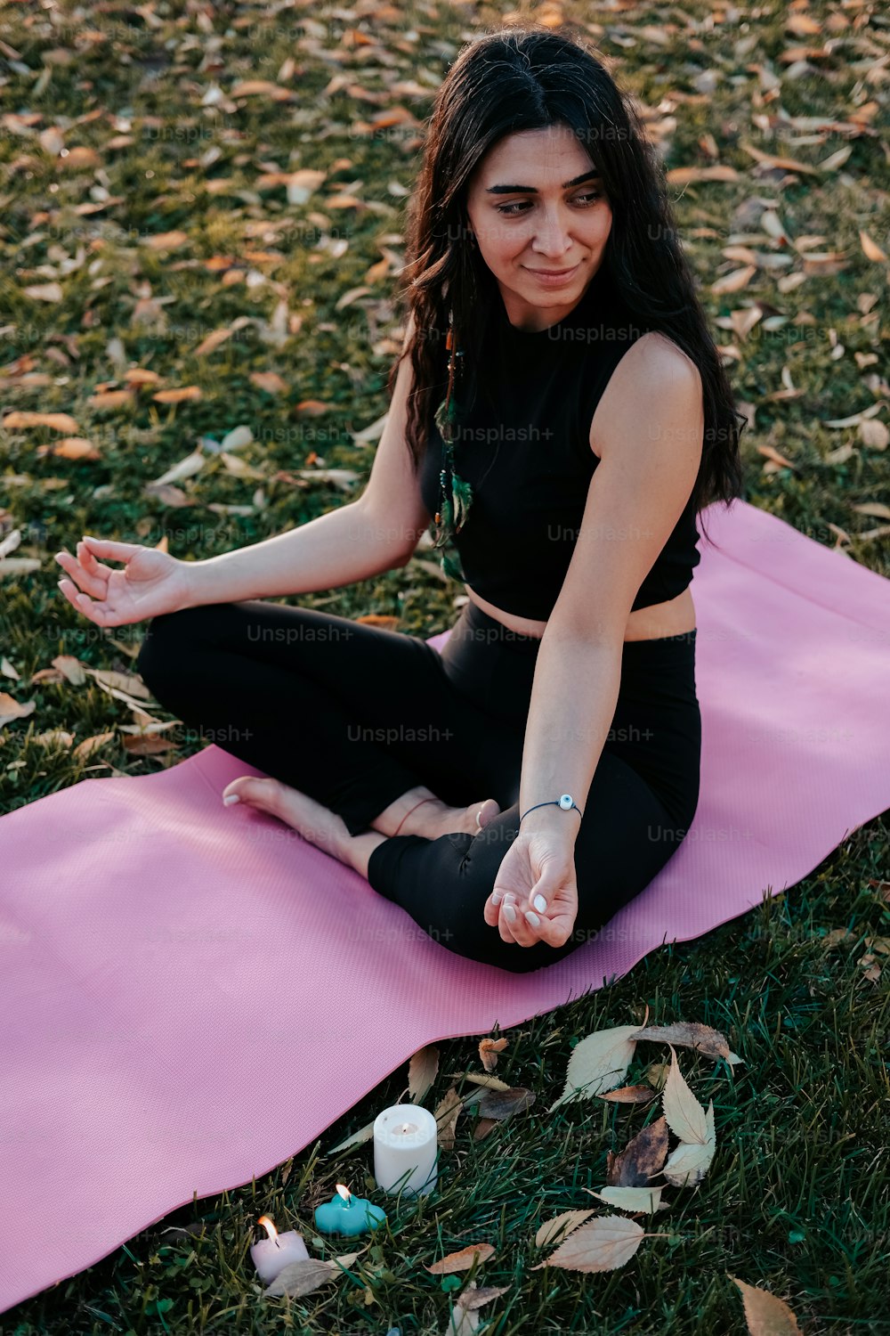 Una donna seduta su un tappetino da yoga in un parco