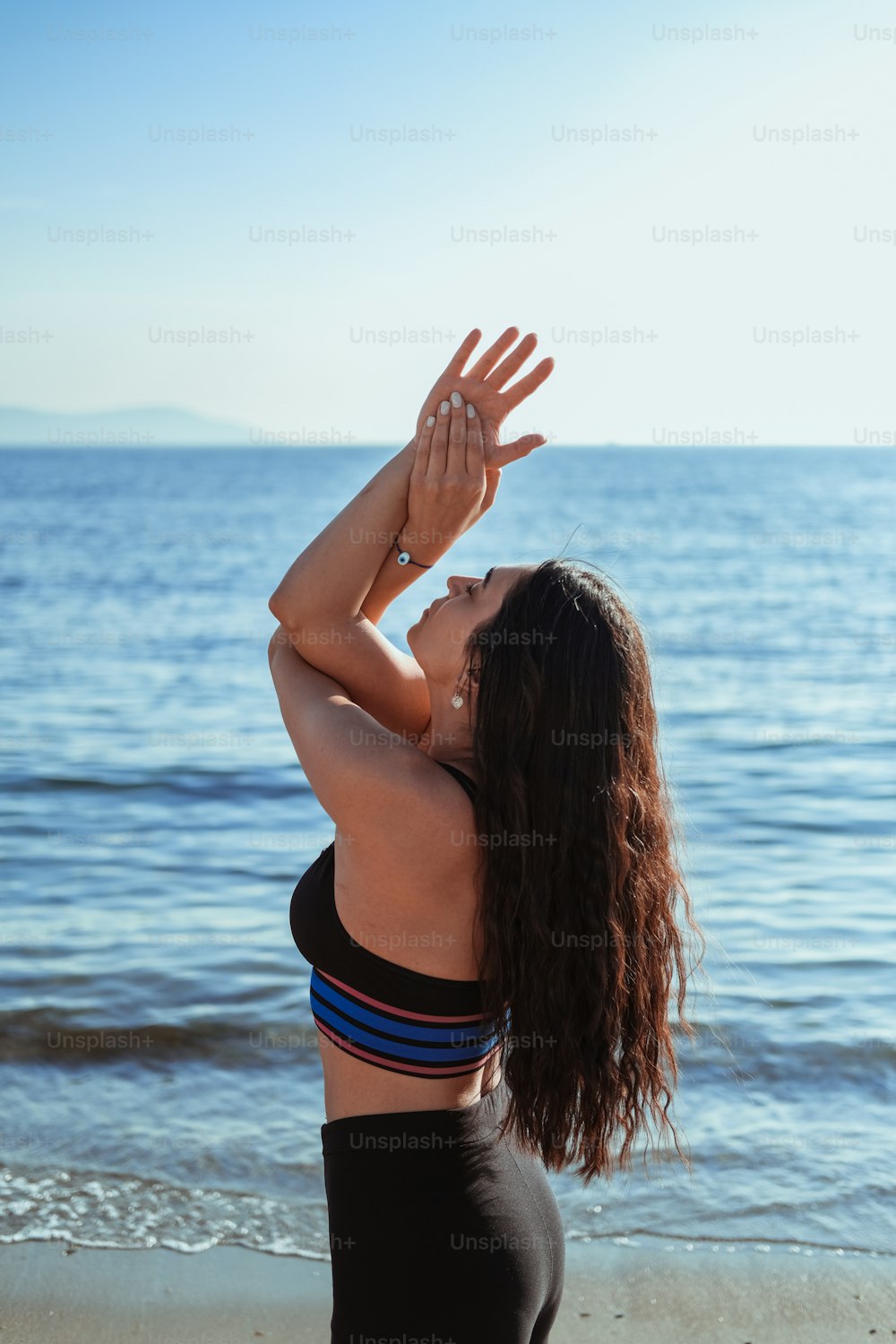 a woman standing on a beach with her hands in the air