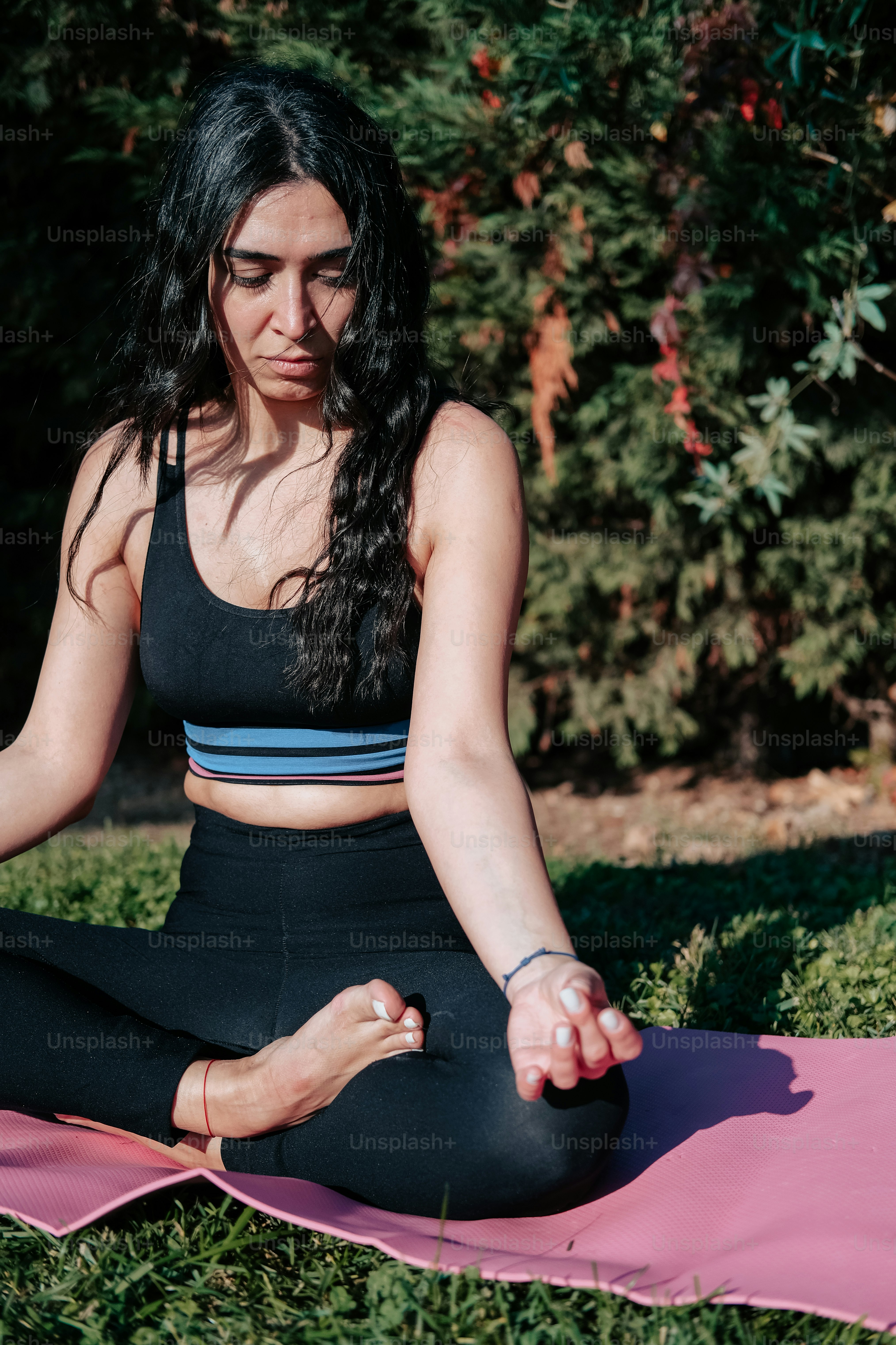 Eine Frau, die in einer Yoga-Position auf einer rosa Matte sitzt