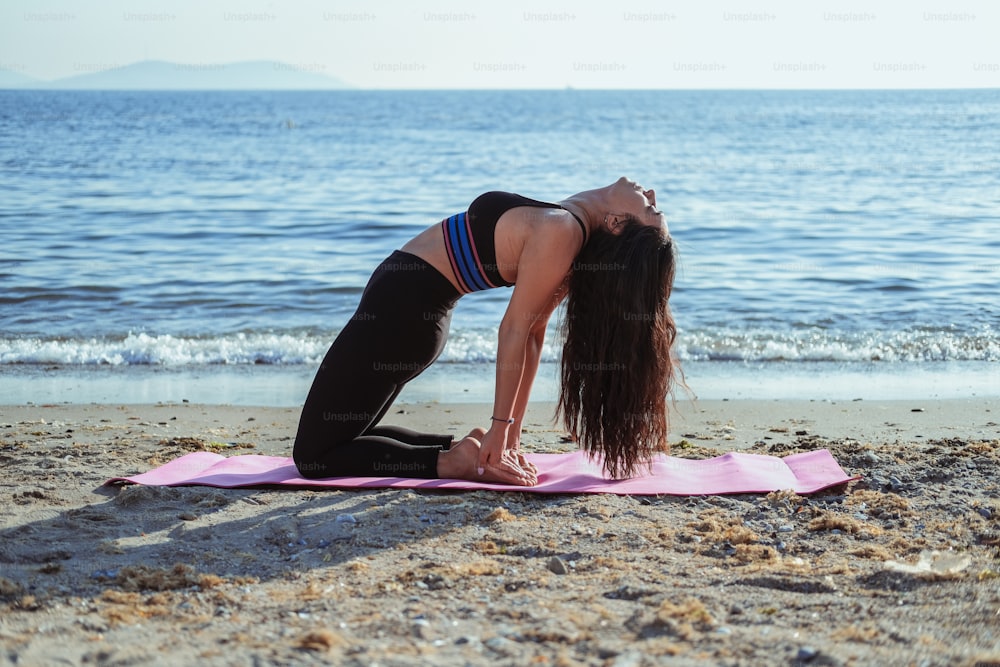 a woman is doing yoga on the beach