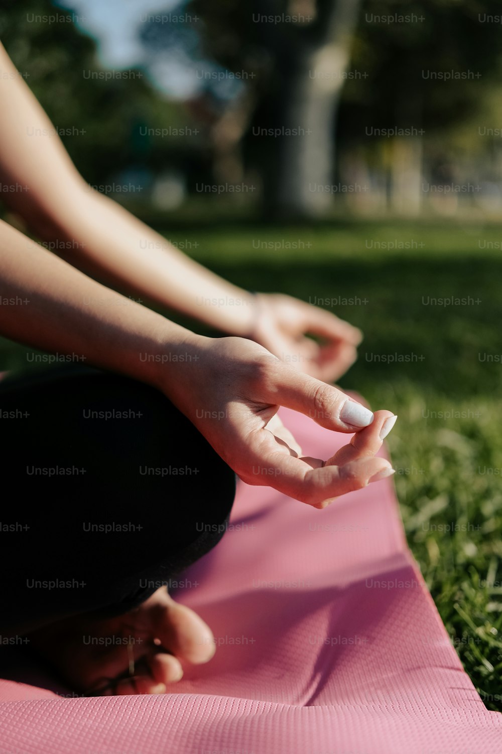 a person sitting on a pink yoga mat in the grass