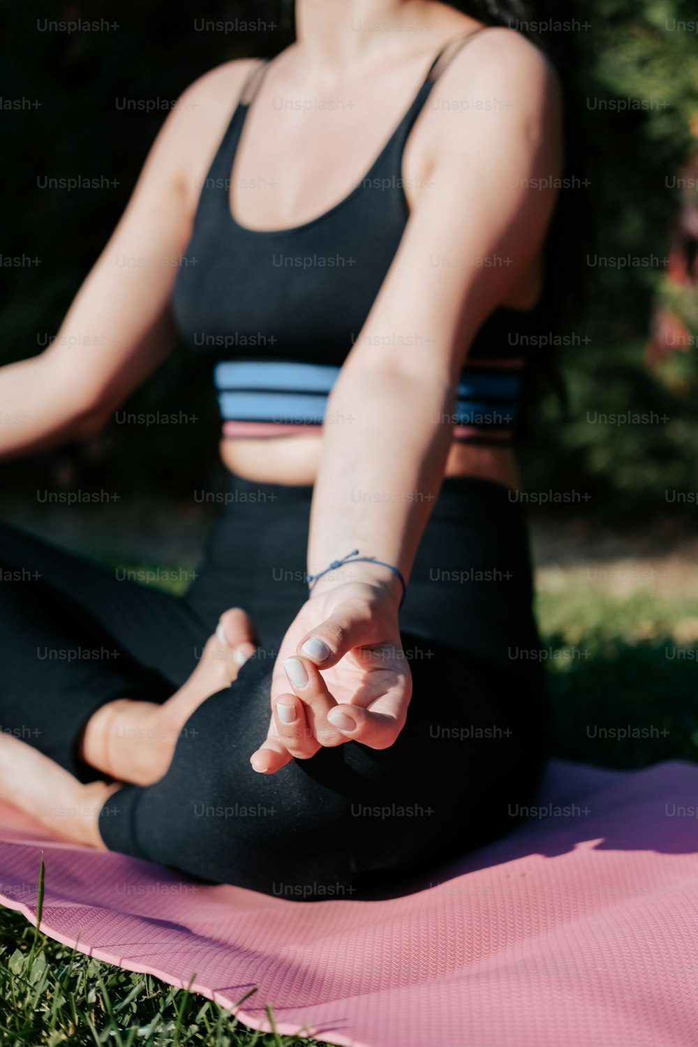 a woman sitting in a yoga position on a pink mat