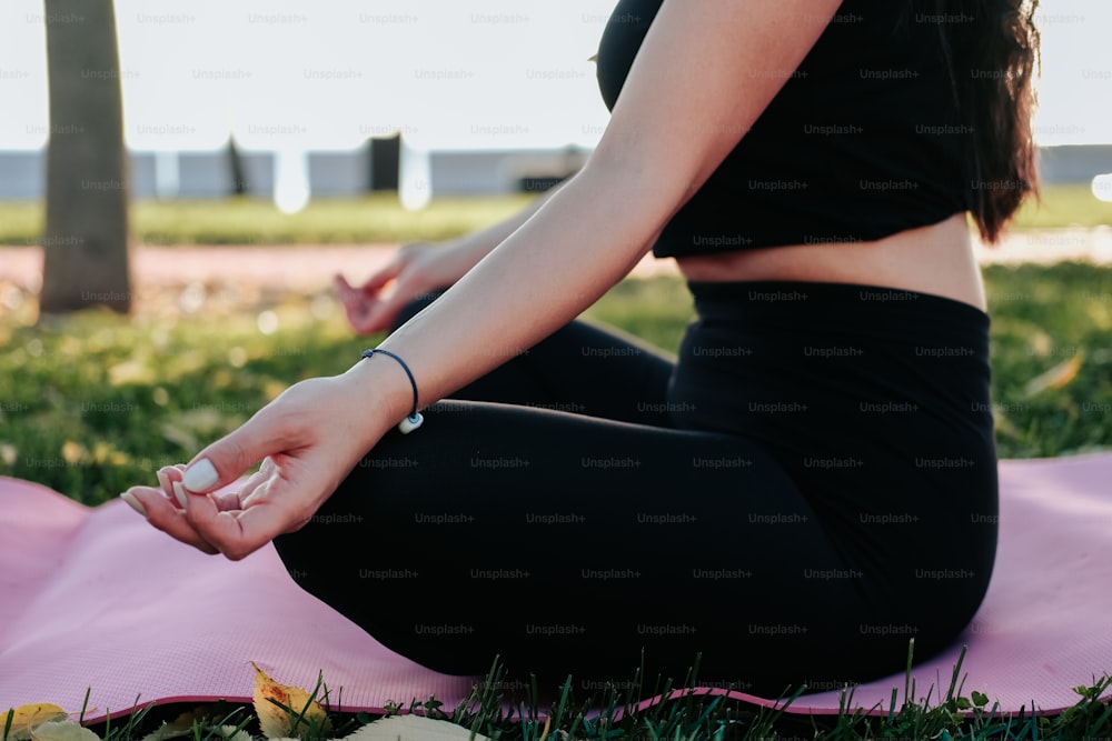 Une femme assise sur un tapis de yoga dans un parc