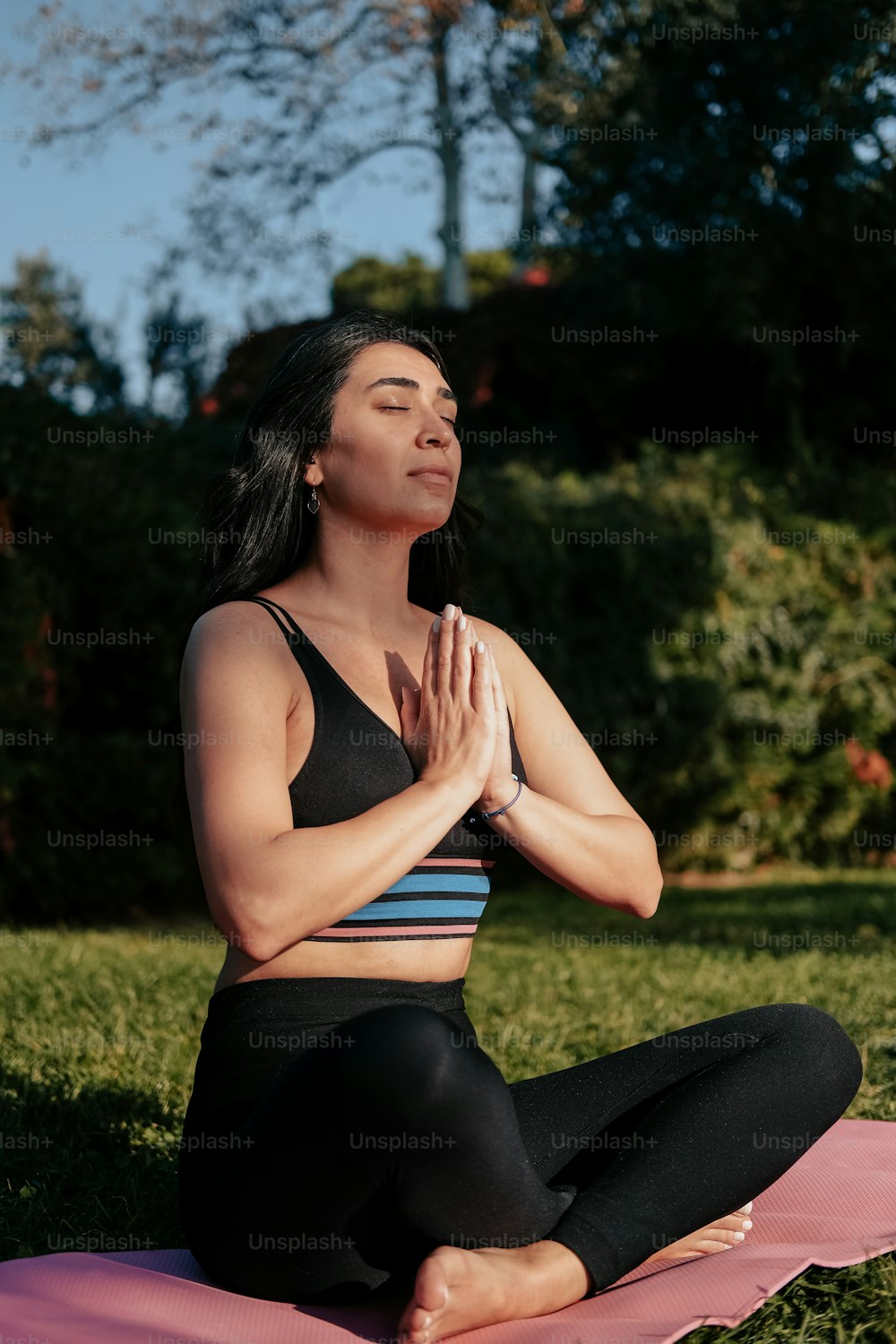a woman sitting on a yoga mat in a park