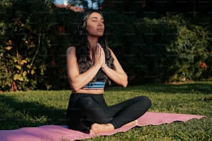 Una mujer sentada en una esterilla de yoga en un parque