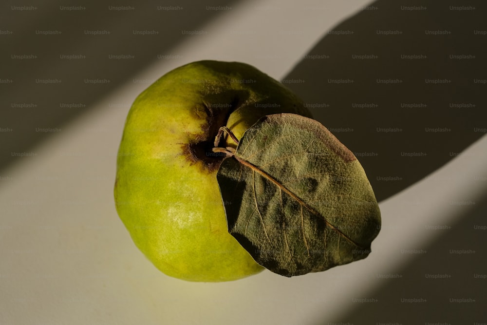uma maçã verde sentada em cima de uma mesa branca
