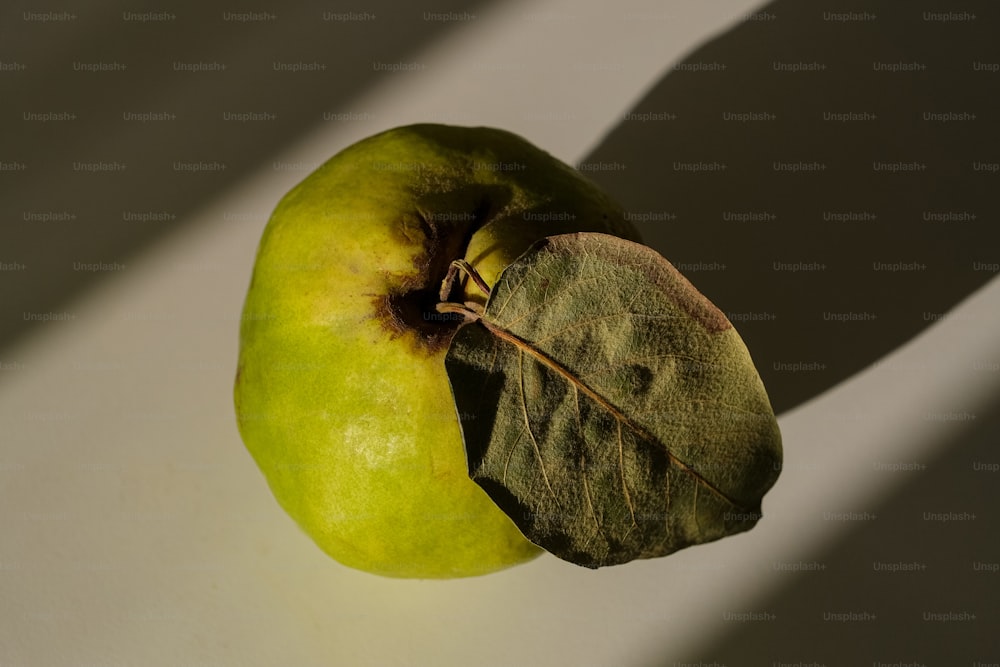 a green apple sitting on top of a white table