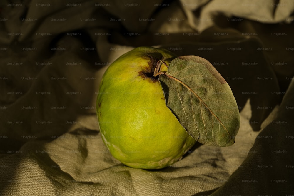 uma maçã verde com uma folha em cima