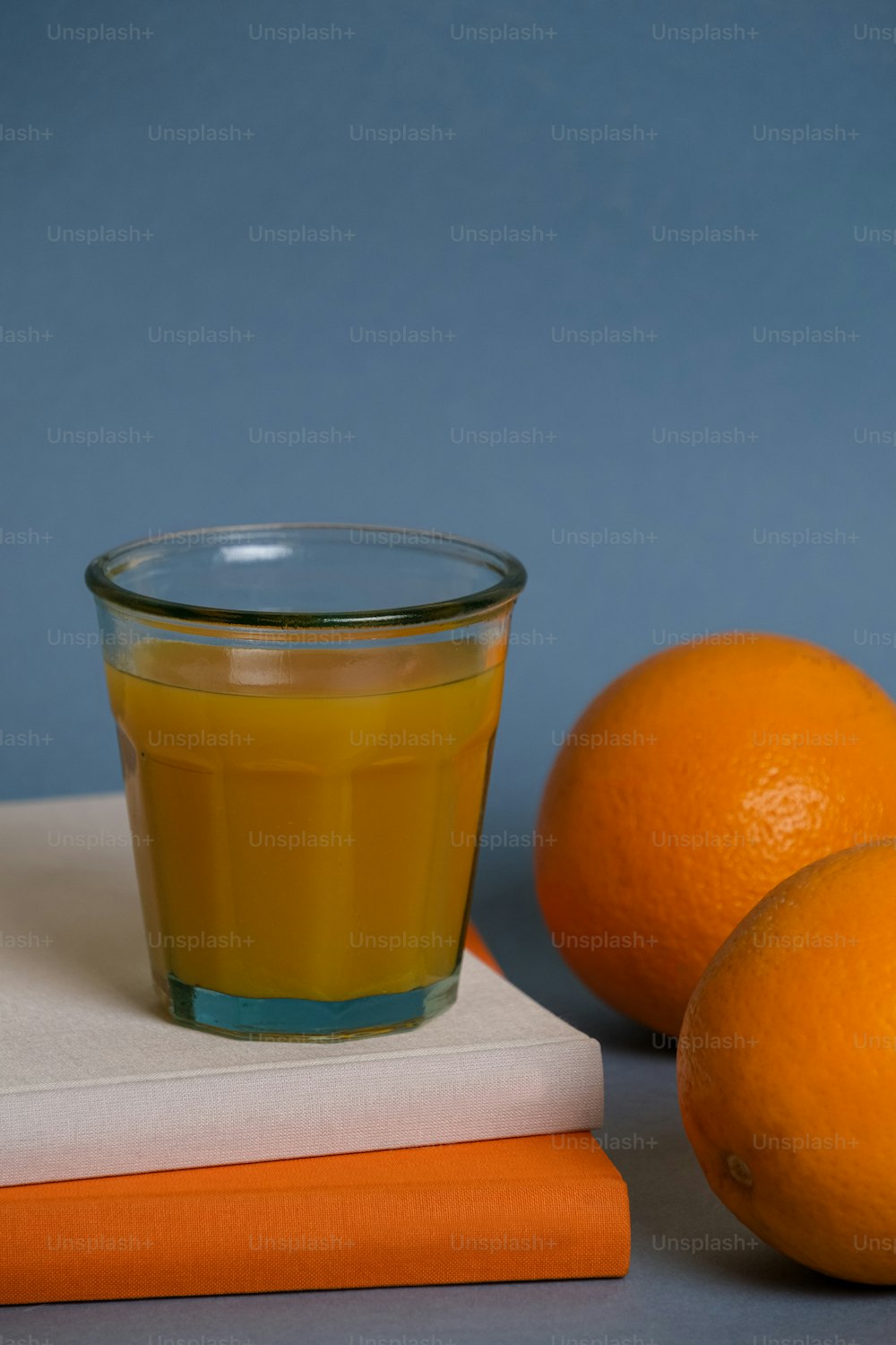 3つのオレンジの横にあるオレンジジュースのグラス